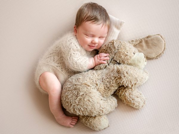 newborn-baby-smiling-while-sleeping-with-toy-dog-newborn-photographer-session.jpg