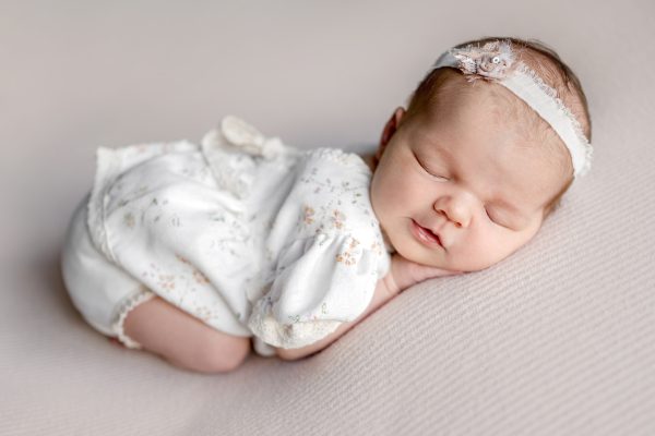 newborn-baby-girl-smiling-sleeping-tummy-dress-photoshoot.jpg