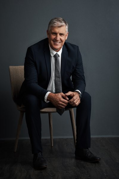 portrait-investor-happy-man-studio-chair-corporate-professional-with-grey-background-mature-person-employee-financial-advisor-with-confidence-about-us-career-ambition-with-pride.jpg