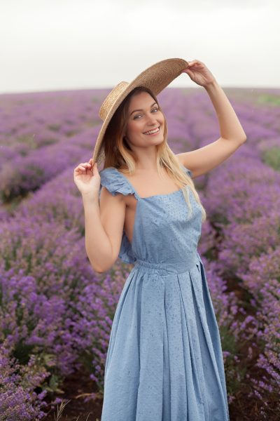blonde-woman-round-wicker-hat-blue-dress-rain-lavender-field-3.jpg