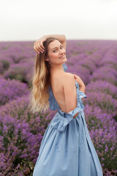 young-smiling-blonde-long-hair-woman-blue-dress-lavender-field-naked-shoulder-posing-model-4.jpg