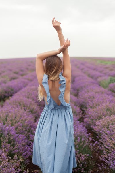 young-smiling-blonde-long-hair-woman-blue-dress-lavender-field-naked-shoulder-posing-model-3.jpg